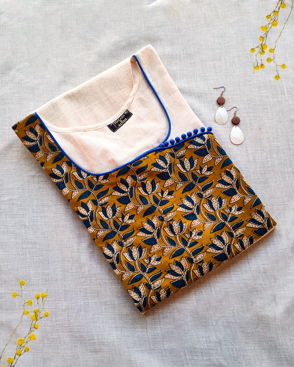 20 Cream Kurta With Blue And Mustard Yoke And Blue Potlis